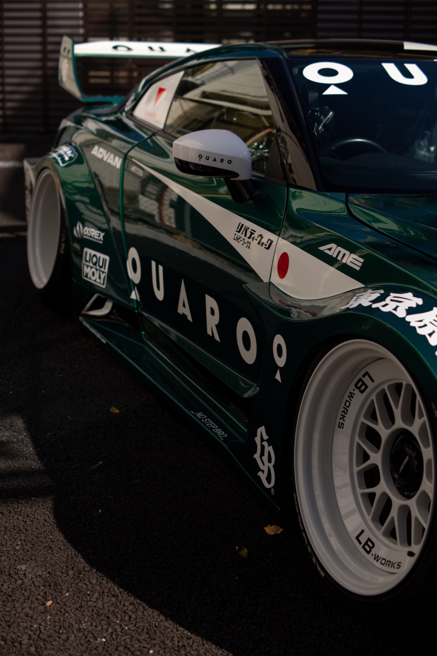 Detail of a green race car's front wheel and bodywork