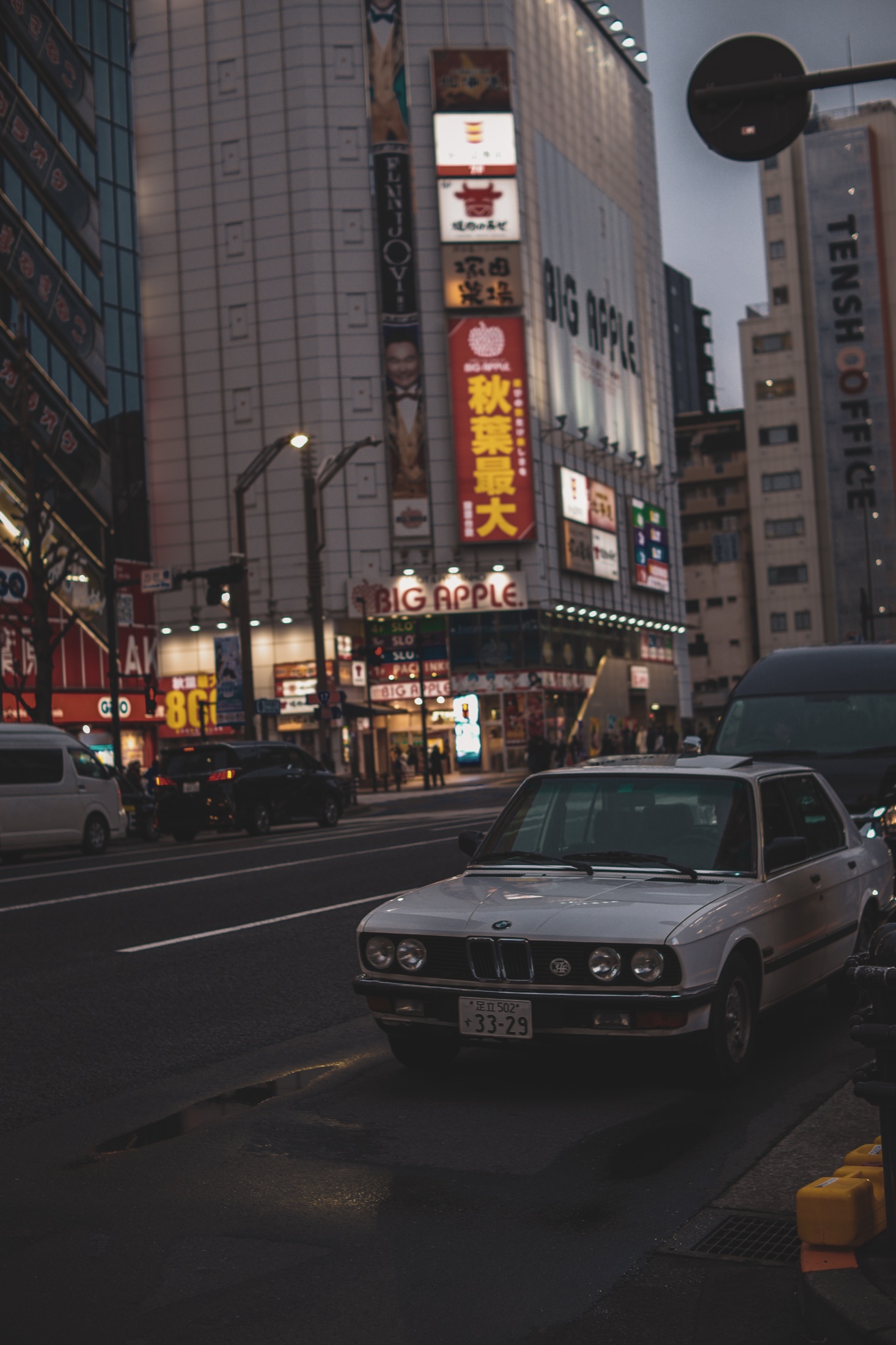 Tokyo street at dusk beneath stacked neon signage