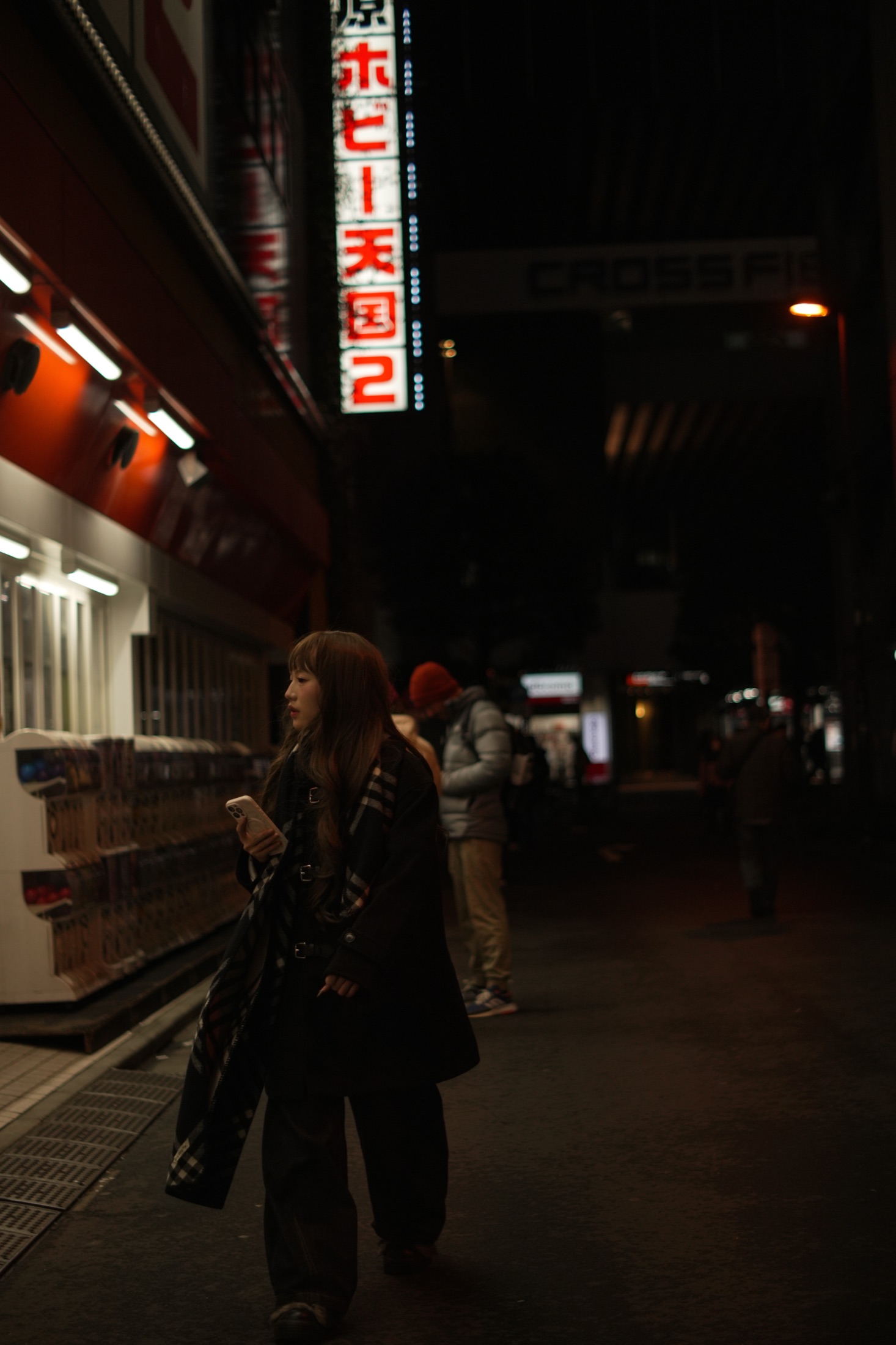 Woman browsing a lit shopfront at night