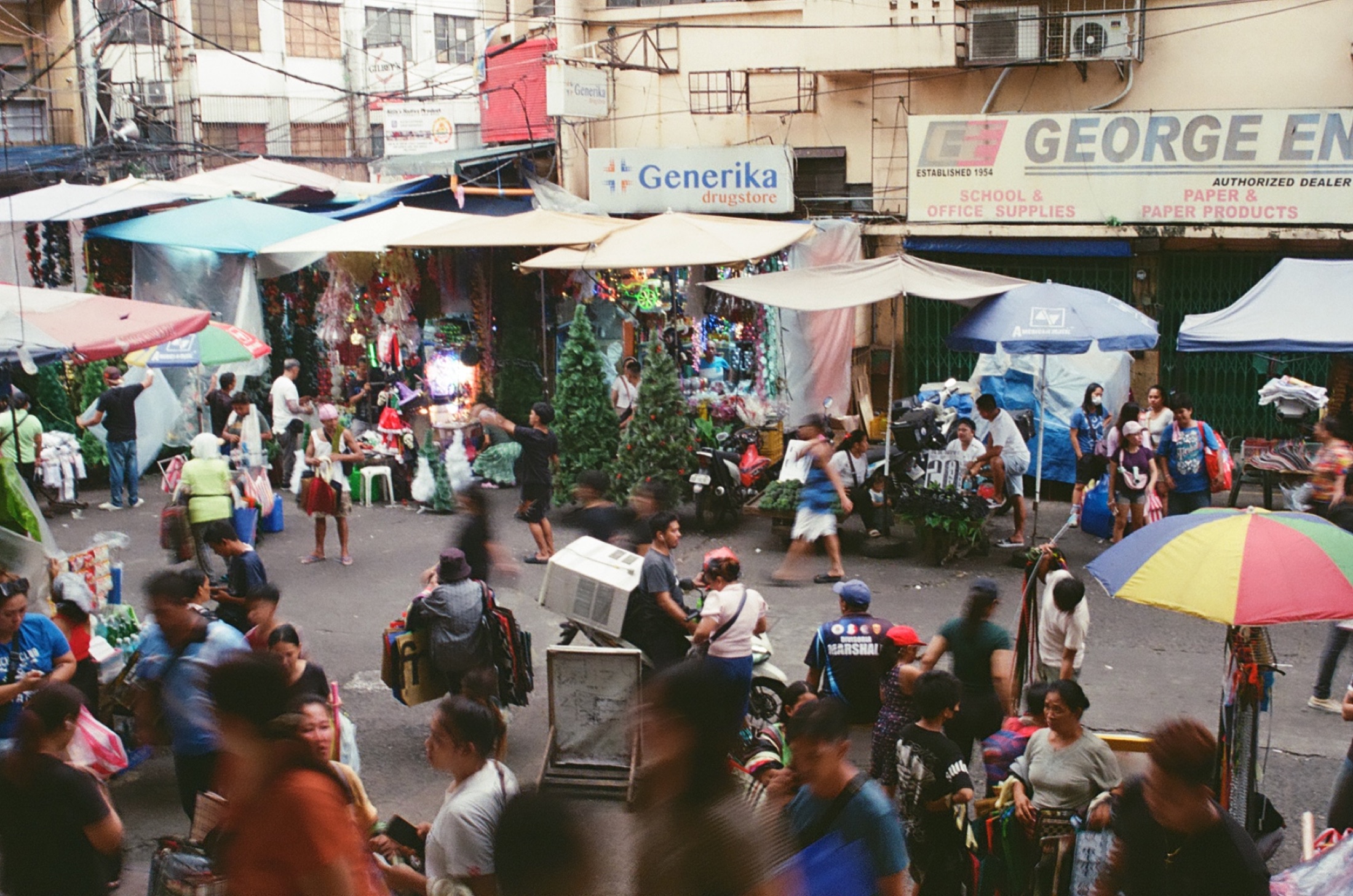 Crowded outdoor market under umbrellas in daylight