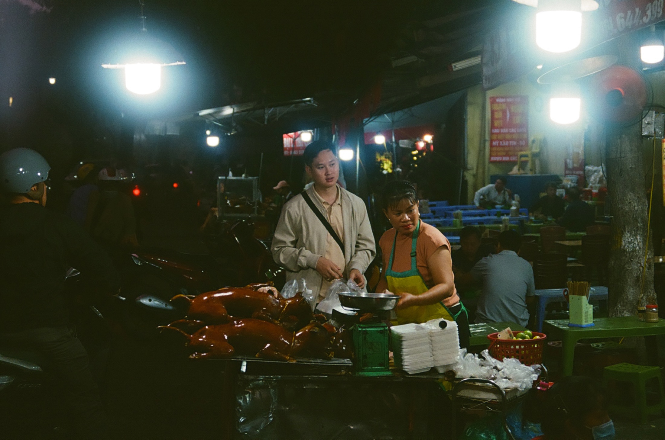 Night food stall, vendors working under hanging bulbs